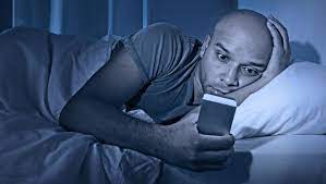 image of man who can't sleep due to cell phone addiction